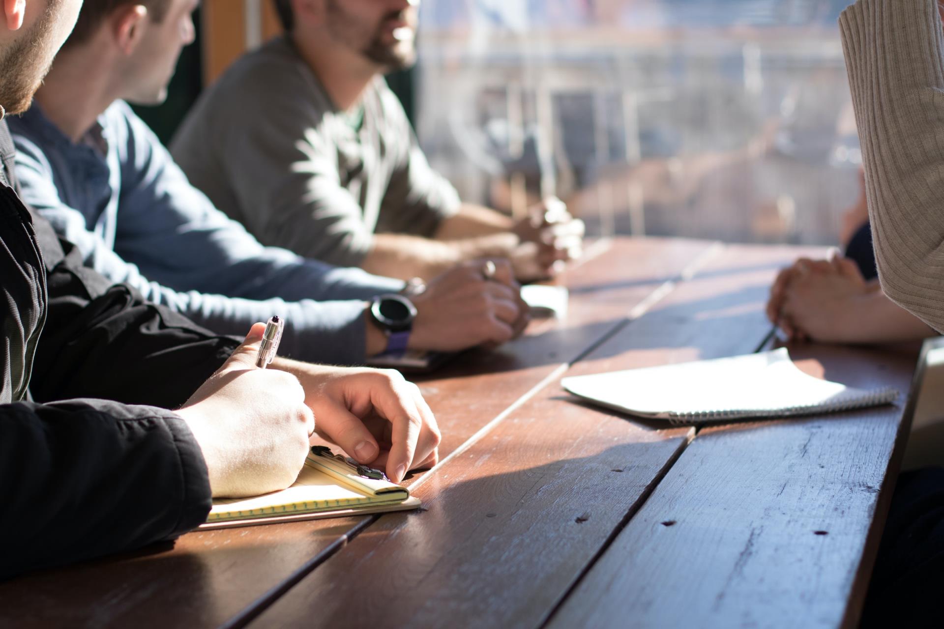 Adults discussing with notebook on table