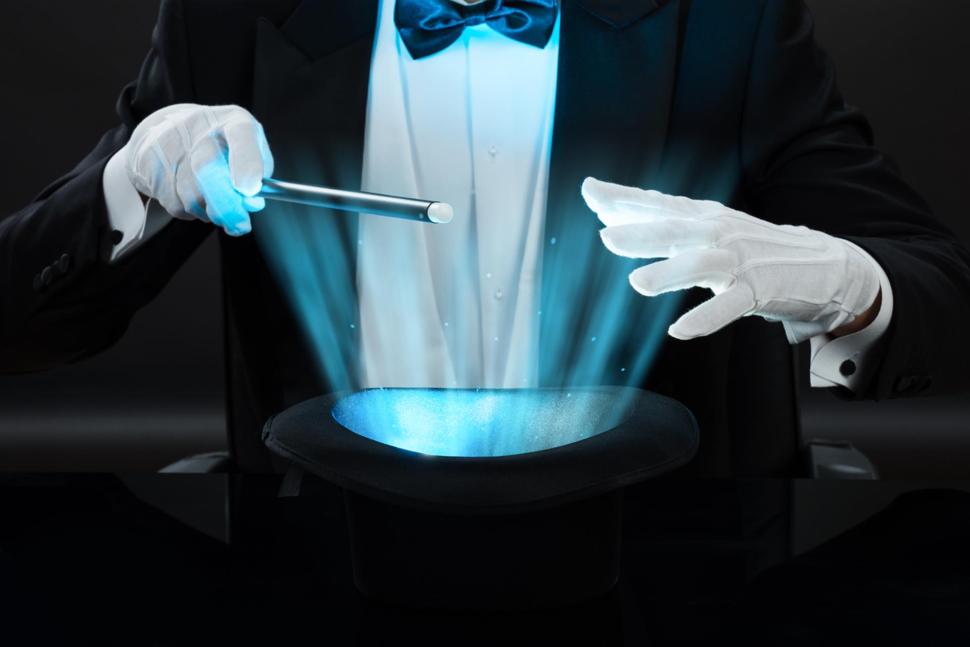 magician's gloved hands over hat with light streaming out