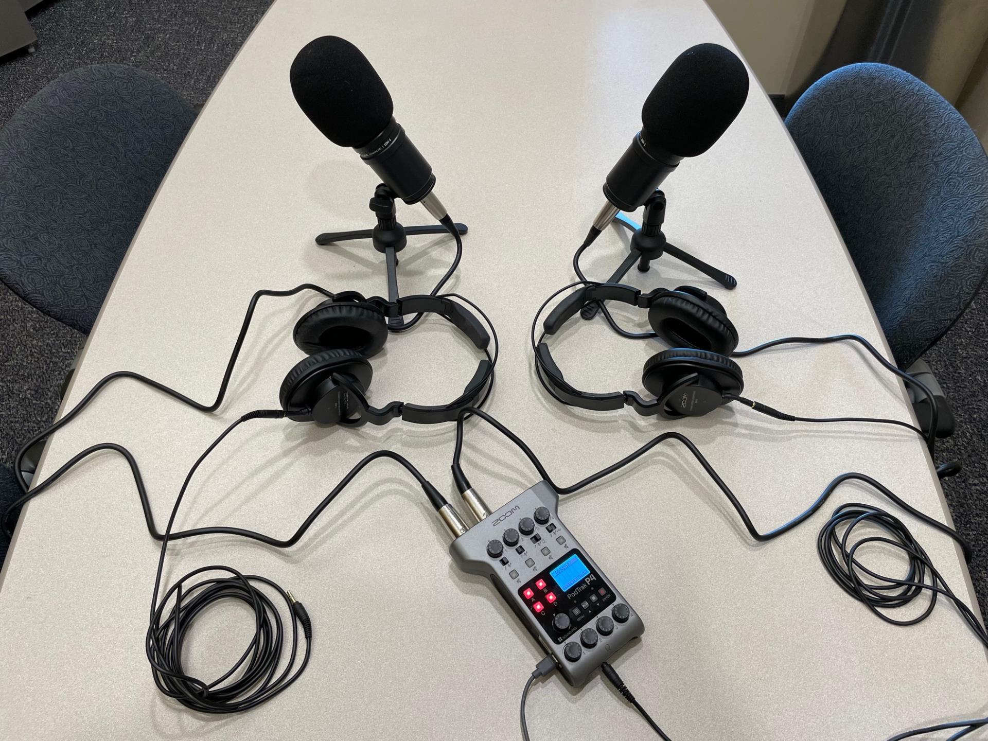 Recording equipment on table including 2 microphones, headphones and a pod track recorder 