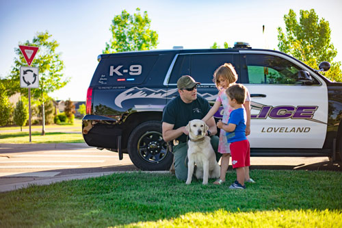 Two children pet a Labrador Retriever from the Loveland Police Canine Unit.