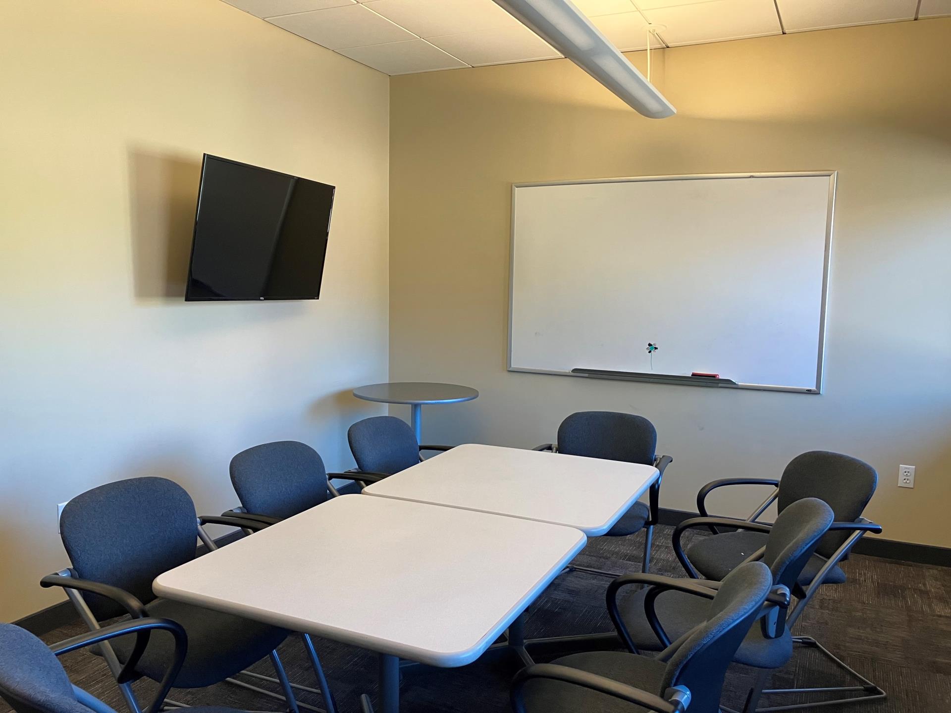 Long white table, TV, whiteboard, and chairs