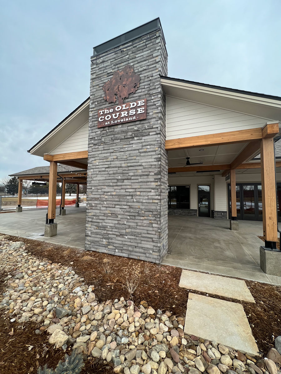 The entrance to the clubhouse at the Olde Course Golf Course. It has a rustic design with a large brick column in the middle.