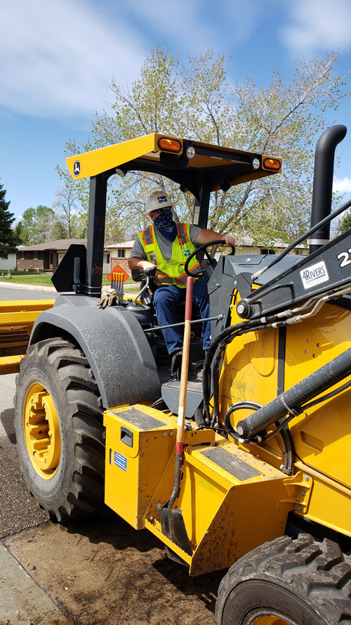 A worker sits atop a milling machine.