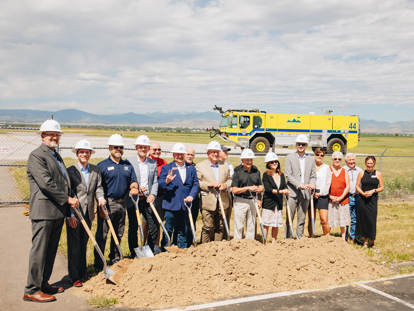 Several people stand with hard hats and shovels.