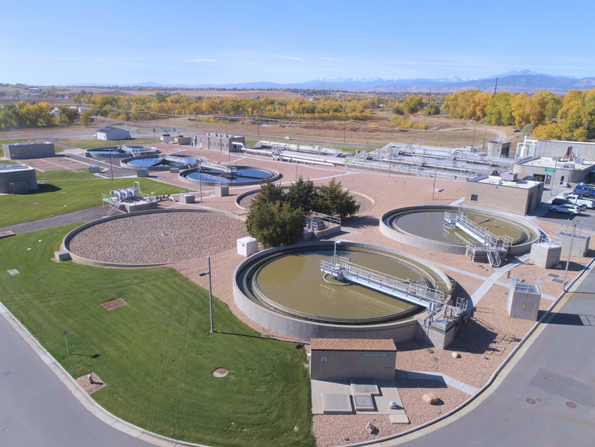 An aerial photograph of the wastewater treatment plant showing large circular clarifiers.