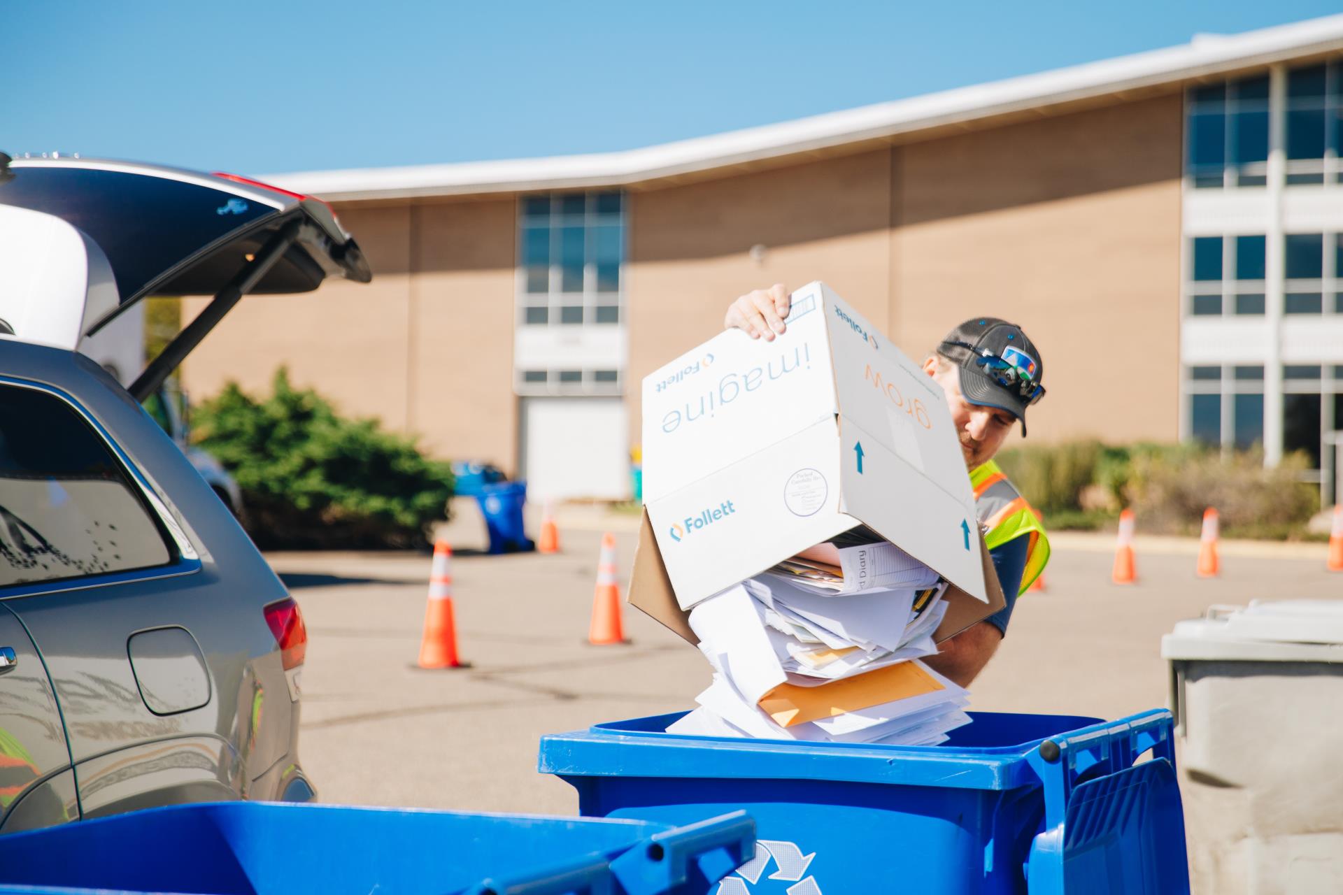 Shred event staff member unloads paper into a recycling cart.