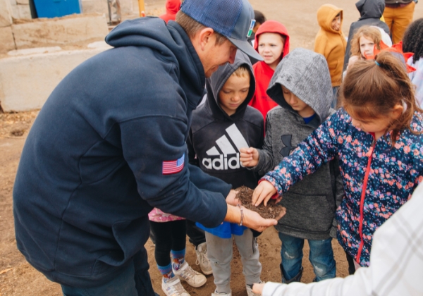 A City staff member showing a group of children a handful of compost at the Recycling Center.