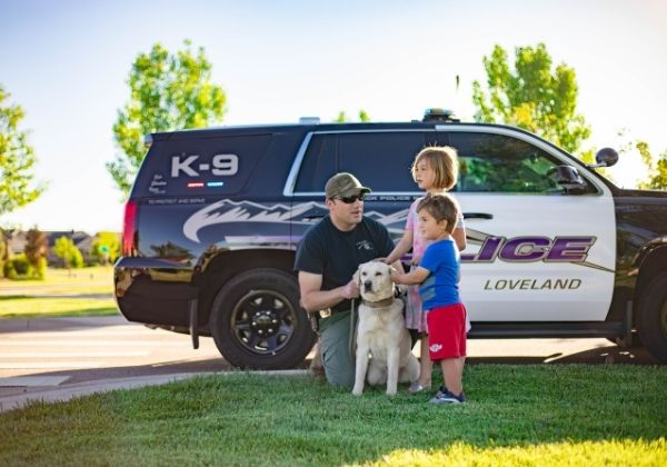 A police officer and dog next to two children.