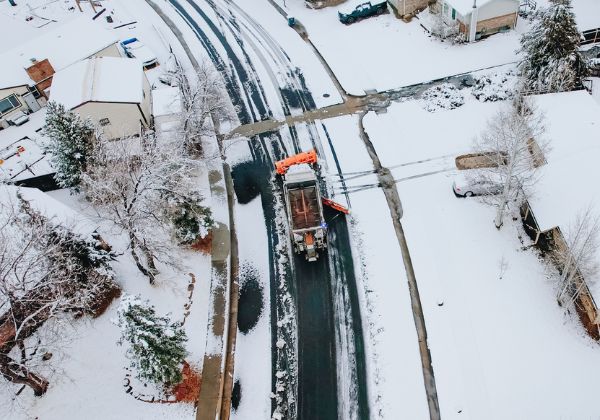 Snowplow clearing a residential street covered in snow during winter.